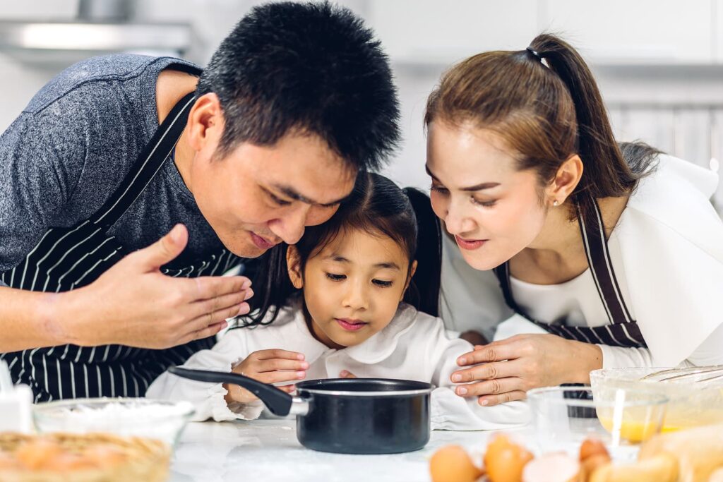 Family cooking over pot in kitchen