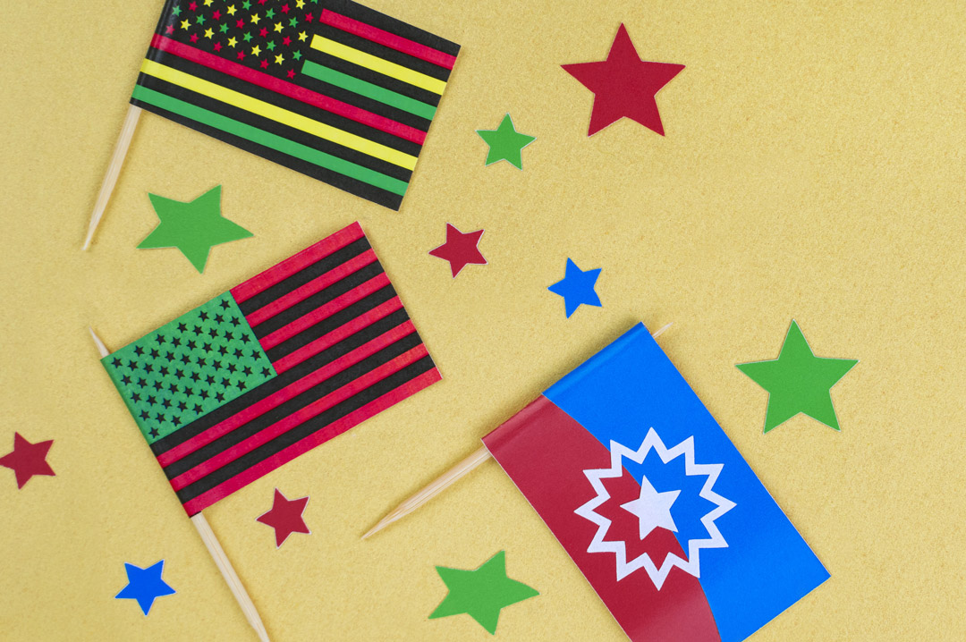 Paper Juneteenth flags and colorful paper stars on brown craft paper